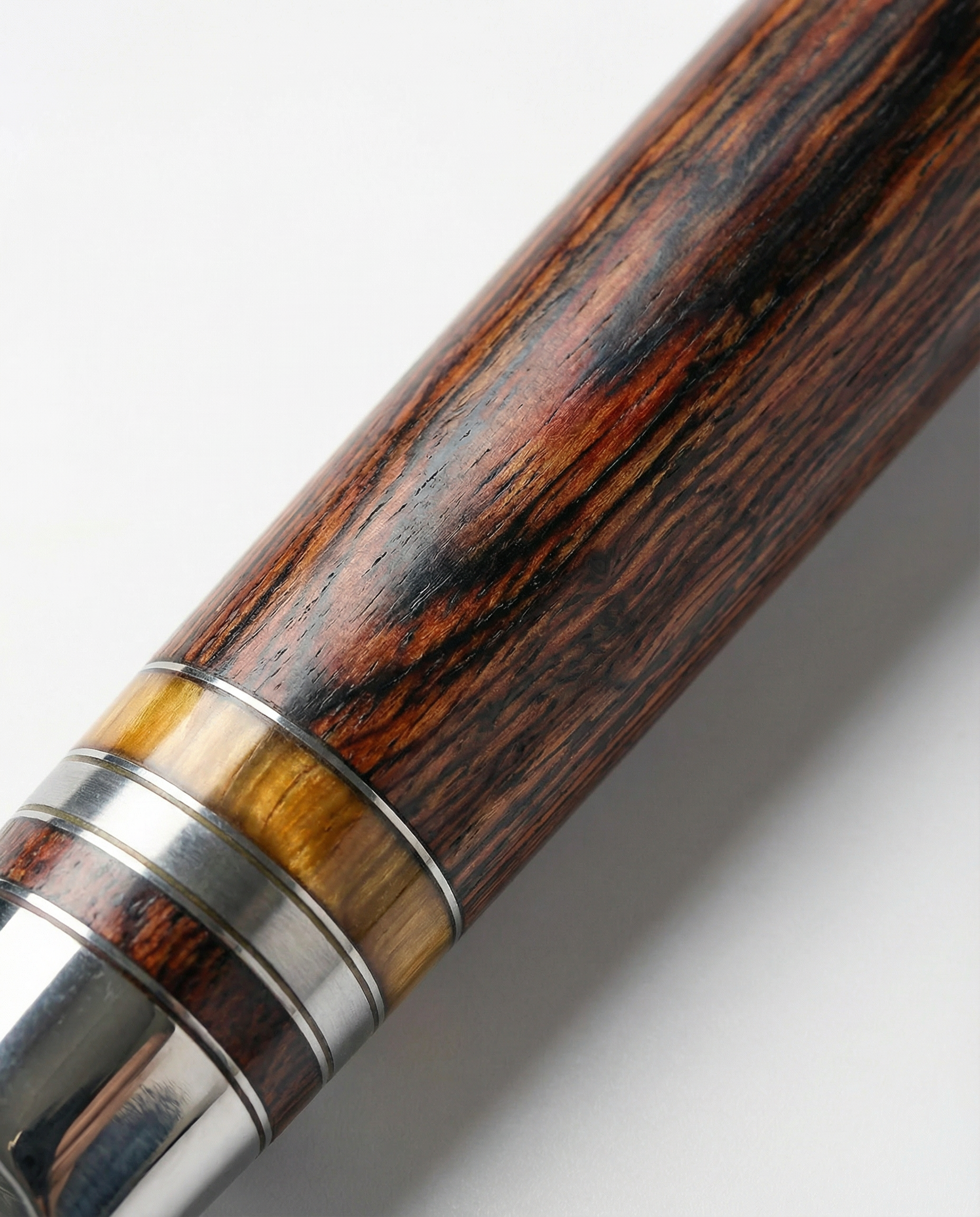 Gros plan sur le manche en bois brun veiné d’un couteau japonais, avec bagues métalliques et insert ambré près de la mitre.