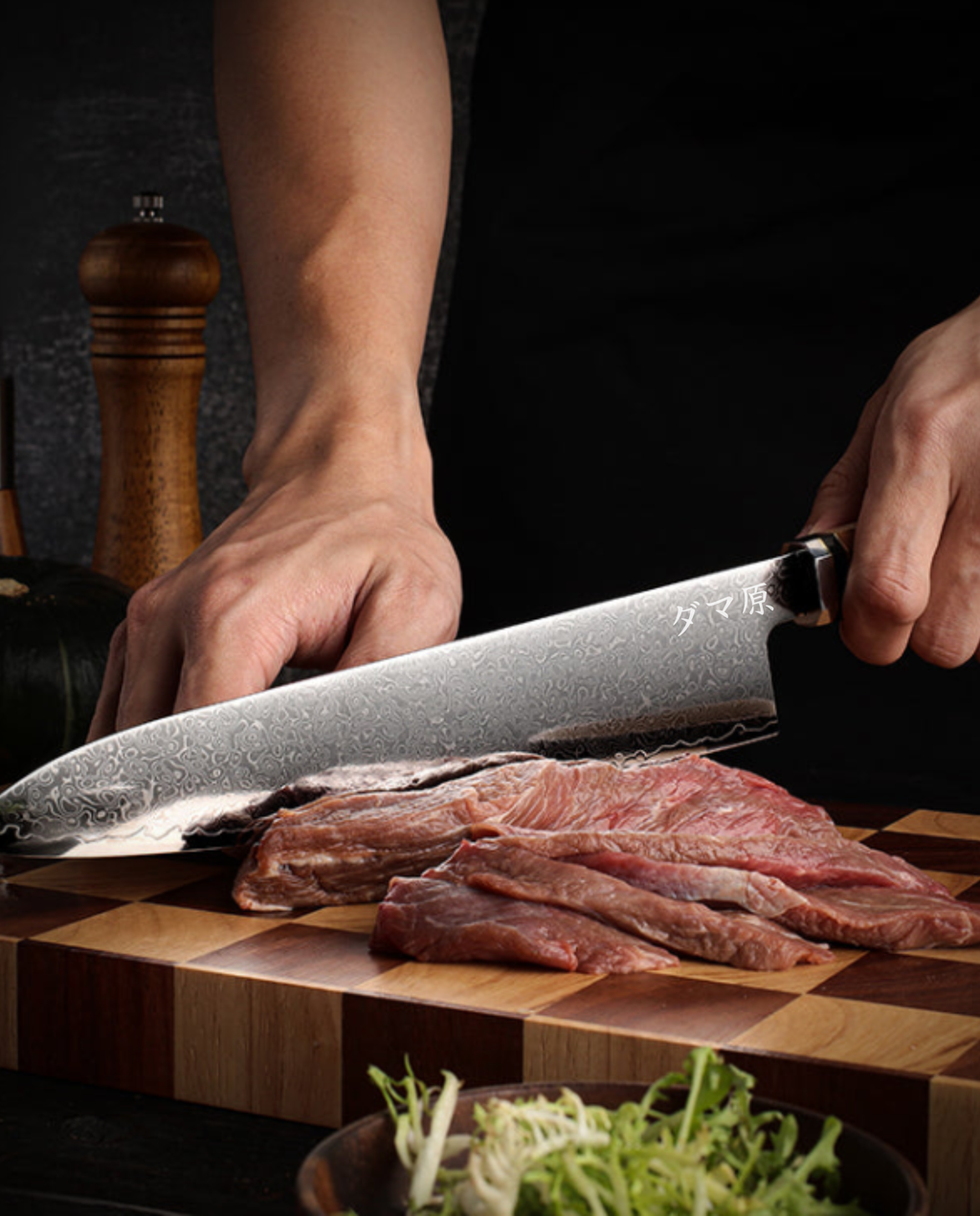 Couteau japonais Gyuto en acier damassé tenu en main en train de trancher de la viande sur planche en bois à damier.
