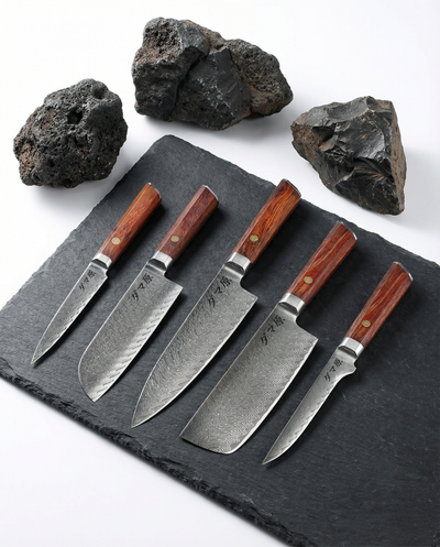 Set de 5 couteaux japonais en acier damassé avec manches bois naturel, présentés sur ardoise noire et pierres volcaniques.