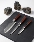 Set de couteaux japonais en damas avec manches en bois, lames martelées ultra tranchantes sur ardoise noire.