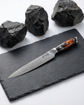 Couteau japonais sujihiki en acier damas, lame longue et fine, manche résine noir et ambre, présenté sur ardoise.