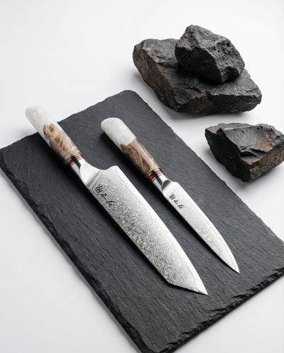 Set de 2 couteaux japonais damas, chef et utilitaire, manches bois et résine blanche sur ardoise noire.