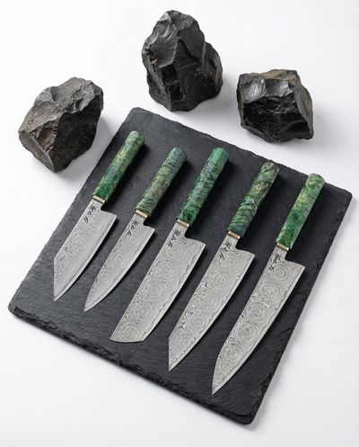 Set de 5 couteaux japonais en acier damas, manches verts texturés, alignés sur ardoise avec pierres décoratives.