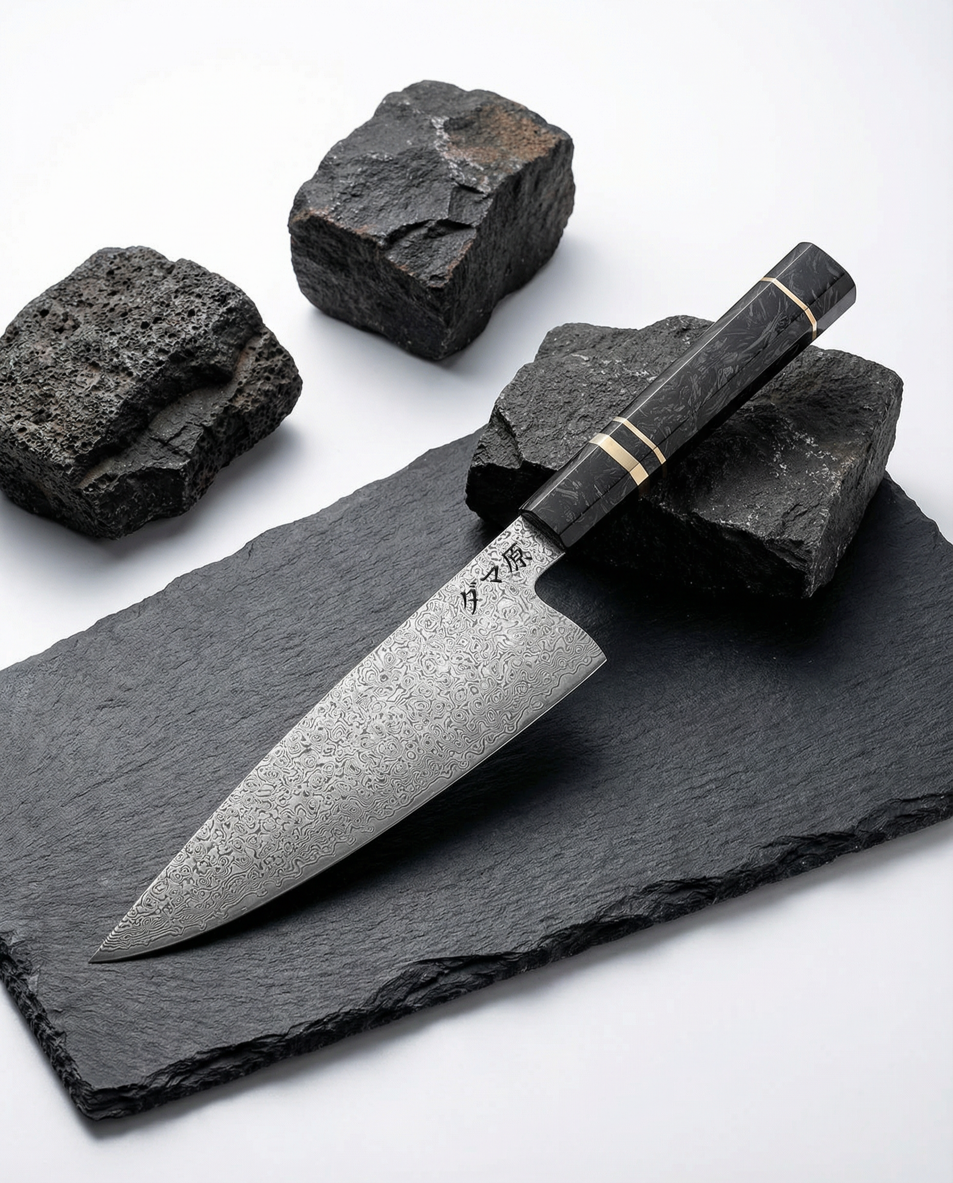Couteau japonais en acier damassé à manche noir veiné avec bague claire, posé sur ardoise noire entourée de pierres brutes