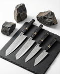 set de couteaux japonais en acier damassé avec manches noirs veinés, posés sur ardoise noire entourée de pierres brutes
