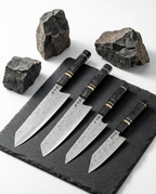 set de couteaux japonais en acier damassé avec manches noirs veinés, posés sur ardoise noire entourée de pierres brutes