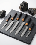 Set complet de 6 couteaux japonais en damas avec manches bois et lames martelées, collection professionnelle sur ardoise noire.