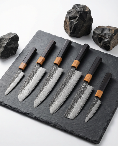 Set complet de 6 couteaux japonais en damas avec manches bois et lames martelées, collection professionnelle sur ardoise noire.
