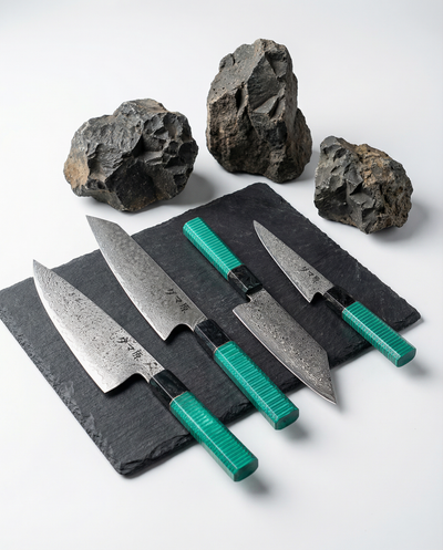Set de 4 couteaux japonais en acier damassé avec manches verts texturés, posés sur ardoise avec pierres brutes