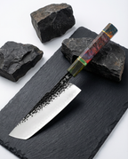 Couteau japonais en acier, manche en bois stabilisé rouge et vert, posé sur ardoise noire avec pierres sombres