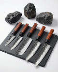 Set de cinq couteaux japonais en acier martelé, manches en bois brun, alignés sur ardoise avec pierres brutes