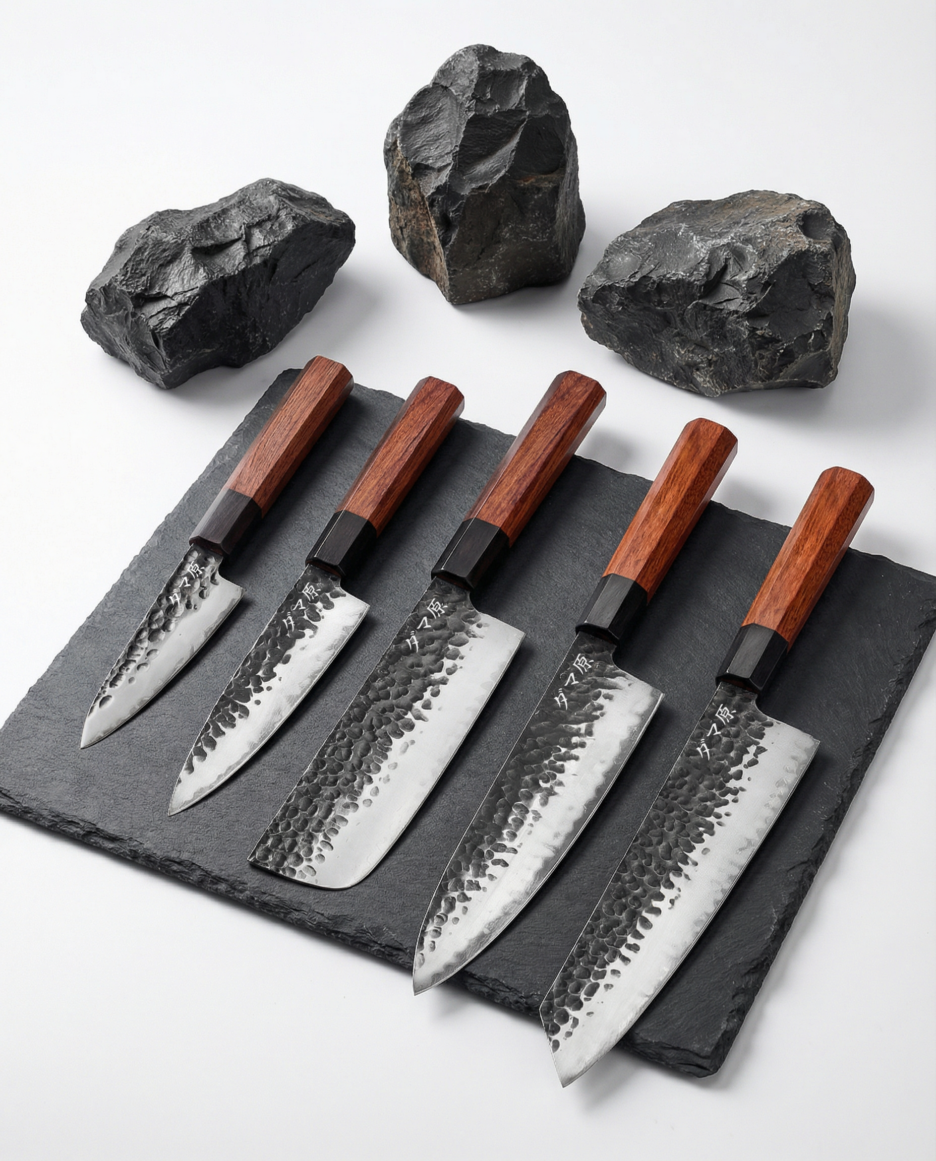 Set de cinq couteaux japonais en acier martelé, manches en bois brun, alignés sur ardoise avec pierres brutes